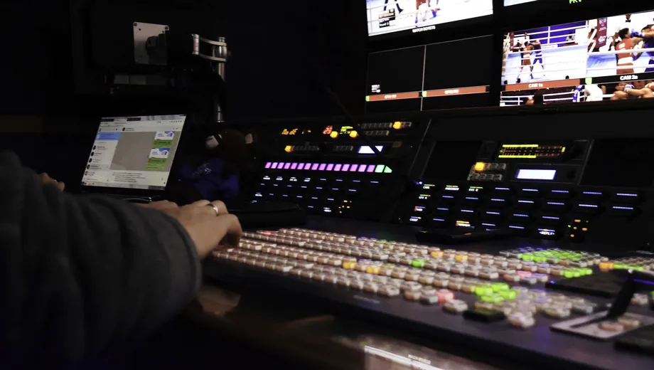 Operator at a multi-screen streaming desk watching latency