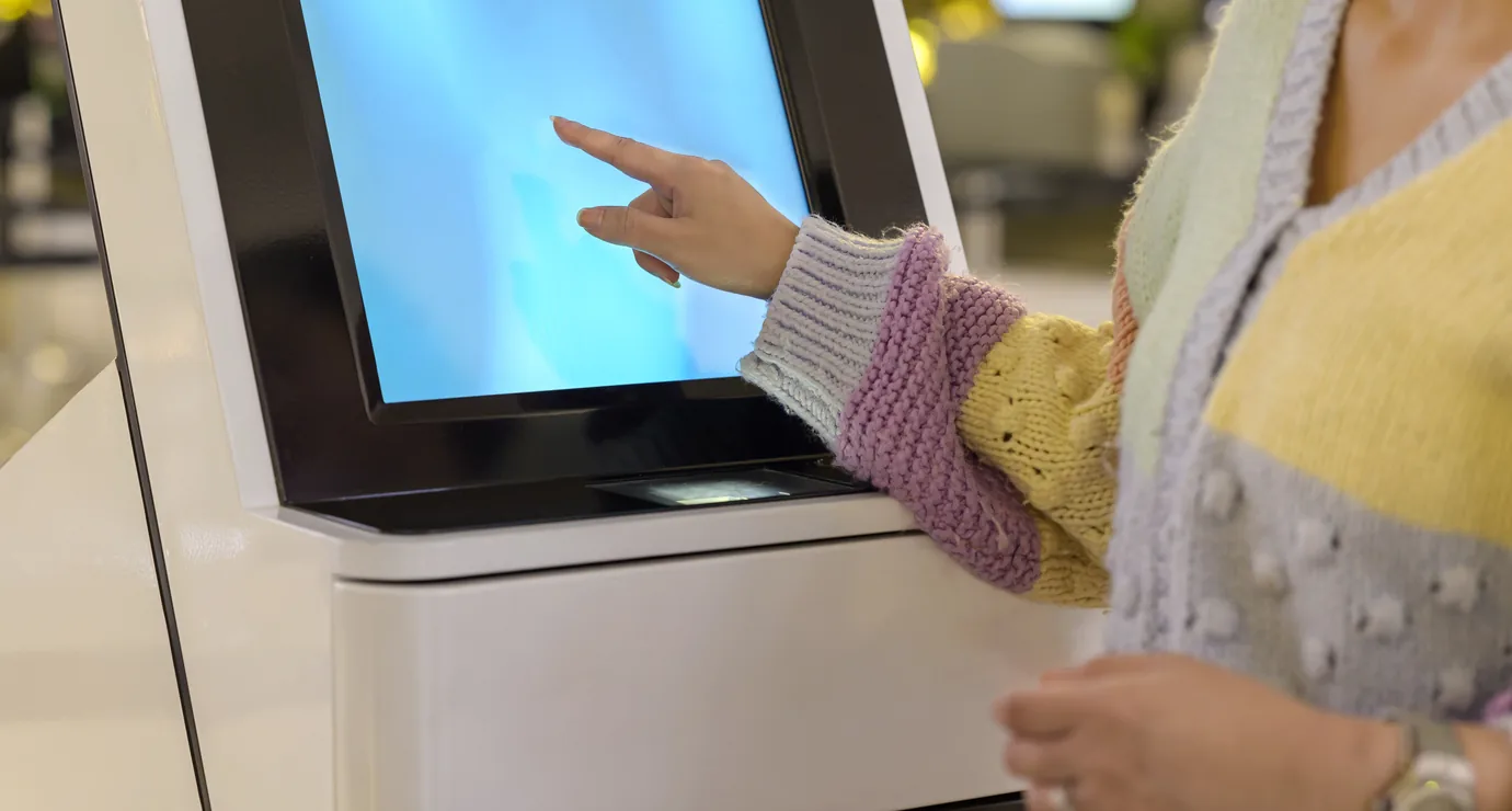 Attendee checking in at a self-service kiosk touchscreen